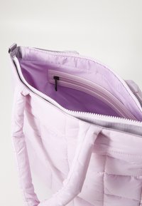 Ljust lila kviltad tote-väska med dragkedjestängning och slät innerfoder. Har en liten innerficka för säker förvaring.