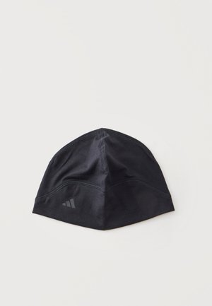 Czarna sportowa czapka typu beanie z subtelnymi przeszyciami i małym odblaskowym logo po jednej stronie, ułożona płasko na białym tle.