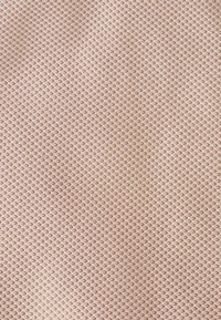 Tissu textile au motif en diamants, avec une base marron clair et des accents blancs. Texture lisse et design uniforme tout au long.