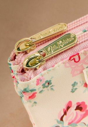 Lähivõte lillemustriga kangast kotikesest, millel on roosa lukk ja kaks kuldse tooniga lukukinnitust, millele on reljeefne kiri "Cath Kidston".