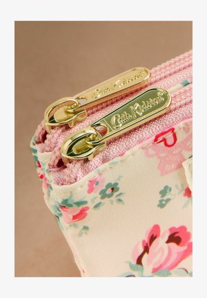 Primer plano de un bolso de tela con estampado floral, cremallera rosa y dos tiradores de cremallera en tono dorado con la inscripción "Cath Kidston" embossada.