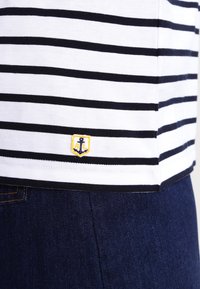 Gestreept t-shirt in wit en marineblauw, met een klein geborduurd ankerlogo in geel op de onderste linkerzijde, gemaakt van zachte katoen.