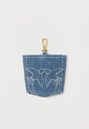 Poche en denim avec un dessin d'oiseau blanc brodé et un clip métallique doré attaché en haut au centre.
