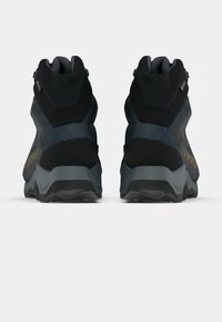 Botas de caminhada de cano médio em preto e cinza escuro, apresentando um upper texturizado, calcanhar reforçado e uma sola exterior de borracha durável com um padrão de aderência.