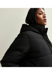 Zwarte gewatteerde jas met capuchon, voorzien van een gestikte textuur en drukknoopsluiting. Slim fit met een hoge kraag, ontworpen voor warmte.