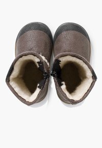 Botas de cuero marrón con un exterior texturizado, punteras negras y un forro de crema suave. Incluyen un detalle de cremallera en el lado.