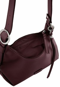 Sac à main en cuir bordeaux de forme arrondie, avec des finitions en métal argenté, une poche zippée et une finition texturée. Dispose d'une sangle réglable.