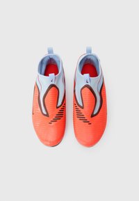 Ζευγάρι φωτεινών πορτοκαλί αθλητικών παπουτσιών slip-on με μαύρες λεπτομέρει�ες και ανοιχτό μπλε κάλτσες αστραγάλου σε λευκό φόντο.