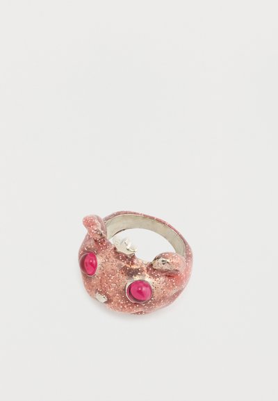 Rosa Glitzer-Ring mit abgerundetem Design, der zwei rote Steine als Augen, metallische Akzente und ein glattes Band aufweist. Hervorzuheben ist seine verspielte Form.
