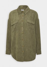 Camisa de pana verde con un frente abotonado, un collar clásico, dos bolsillos en el pecho y un dobladillo redondeado.