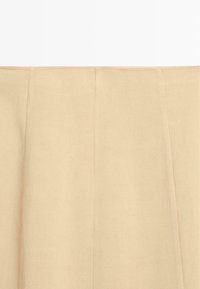 Beige fabric with subtle vertical seams and a smooth woven texture, shown in close-up against a plain light background.