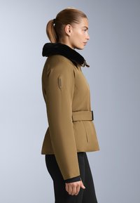 Brown outerwear jacket with a black fur collar, belted waist, and a smooth fabric texture. Features an emblem on the left shoulder.