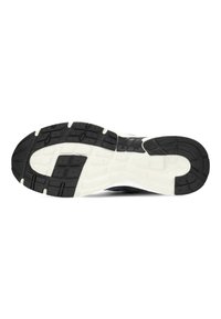 Suola di una scarpa sportiva bianca e nera che mostra schemi di presa texture per trazione e stabilità.
