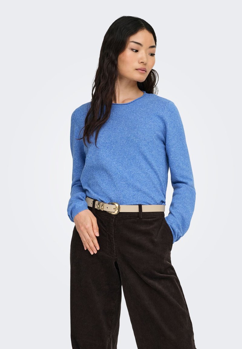 Blauwe trui met een ronde hals, zachte textuur en lange mouwen, gecombineerd met donkere ribfluwelen broek en een lichtbeige riem.