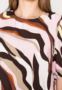 Top a maniche corte con un motivo vorticoso nei colori rosa, marrone, arancione e beige. Tessuto leggero e testurizzato con scollatura rotonda.