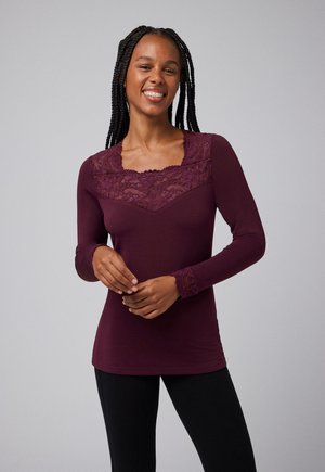 Camiseta de manga larga en púrpura oscuro con detalles de encaje en el escote y los puños. Tejido suave con un diseño ajustado.