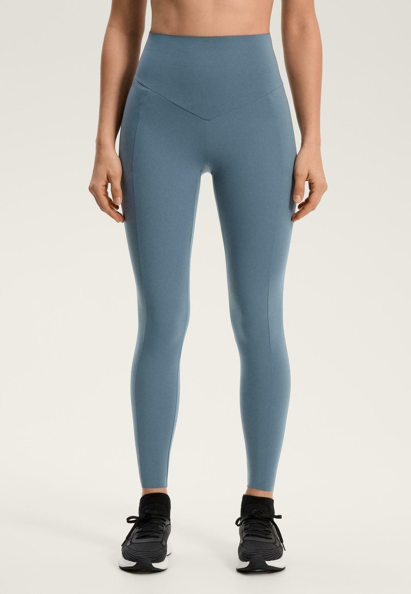 Visoko pasne, oprijete pajkice iz mehke modre tkanine. Imajo šive vzdolž nog in so kombinirane s črnimi športnimi copati.