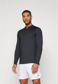 Ilgais rankoves juodas sportinis marškinėlis su apvalia iškirpte, turintis subtilų logotipą ant apykaklės ir sklandų, lengvą audinį.