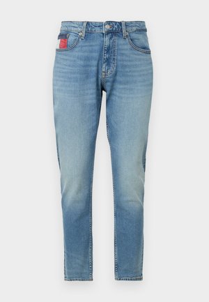 Heledad sinine teksapüksid kitsaste lõigetega, millel on nööbiga sulgemine, viis taskut ja punase-valge aktsendipesa tagataskul.