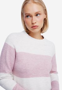 Maglione leggero realizzato in morbido tessuto, con strisce orizzontali bianche e rosa chiaro. Collo rotondo classico e maniche lunghe.