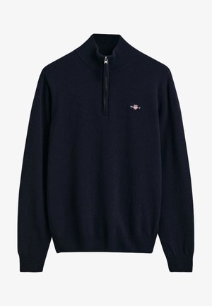 Maglione blu navy con colletto alto e zip a metà, realizzato in un tessuto morbido. Presenta un piccolo logo sul lato sinistro del petto e polsini a coste.