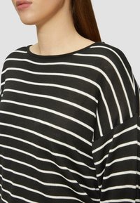 Pull rayé noir et blanc avec un large col, coupe décontractée et texture côtelée, présentant des rayures horizontales et un design à épaules tombantes.