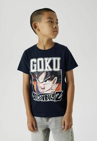 Camiseta de algodón azul marino con un gran gráfico de Goku de Dragon Ball Z, con letras en blanco y naranja en negrita y un diseño de cuello redondo.