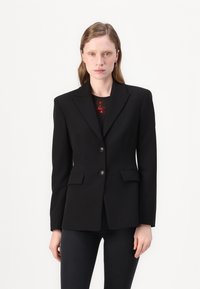 Črn blazer s prilegajočim krojem, dvema sprednjima žepoma in zapiranjem na dva gumb. Ima zarezan ovratnik in gladko teksturo tkanine.