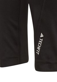 Pantalones cortos deportivos negros con una textura suave y elástica, que presentan el logo "TECHFIT" en blanco y costuras en contraste a lo largo de las costuras.