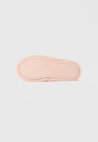 Lyserød plysforet slippersål med tekstureret gummioverflade, der har et gentaget logo. Rundet form med glatte kanter. Blødt, fluffy materiale.