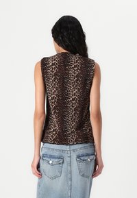 Top senza maniche con stampa animalier e texture plissettata in tonalità di marrone e nero, abbinato a una gonna in denim azzurro chiaro con tasche posteriori.