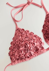 Roze bikini-top met bloemig textuurstof, voorzien van verhoogde driedimensionale rozenpatronen, verstelbare banden en gerimpelde zijkanten.