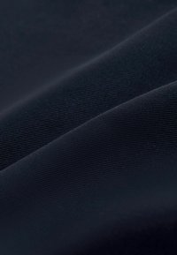 Tissu bleu marine foncé avec une texture fine côtelée horizontale et des plis doux créant des ombres délicates.