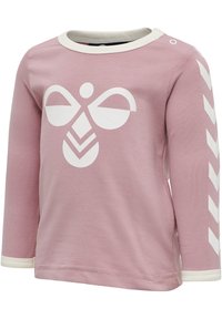 Langærmet pink bomuldsbluse med hvid grafisk design, der viser en sommerfugleform og chevronmønster på ærmerne, fremhævet med hvid kant.