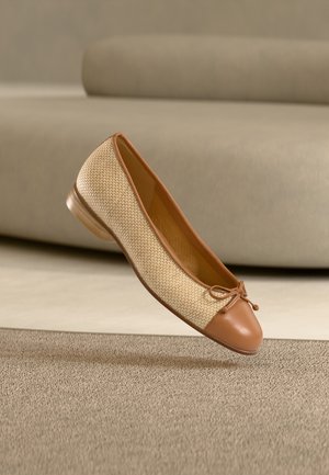 Brun ballerina-sko i skinn og vevd stoff med rundet tå, knytt sløyfdetalj og lav hæl, plassert mot en strukturert bakgrunn.