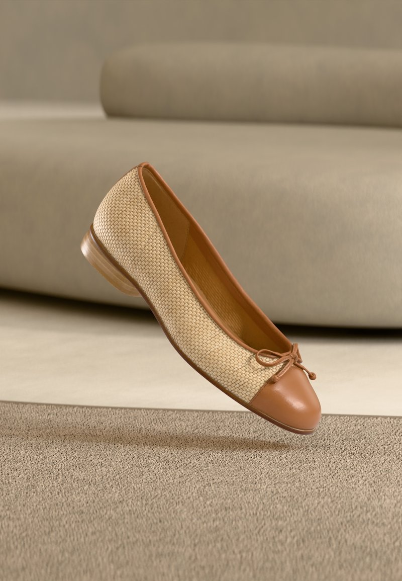 Καφέ δερμάτινο μπαλαρίνα παπούτσι με υφαντό ύφασμα, στρογγυλεμένη μύτη, λεπτομέρεια με δεμένο κορδέλα και χαμηλό τακούνι, τοποθετημένο σε υφασμένο φόντο.