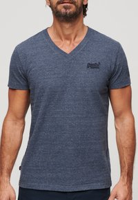 T-shirt navy blu con maniche corte e scollo a V, realizzato in morbido tessuto testurizzato, con un piccolo logo ricamato sulla parte sinistra del petto.