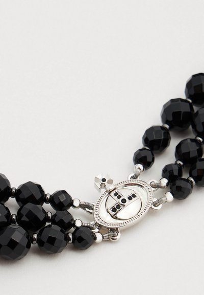Μαύρο βραχιόλι με χάντρες, που διαθέτει πολύεδρες μαύρες γυάλινες χάντρες και κούμπωμα σε ασημί απόχρωση με οβάλ σχέδιο και διακοσμητικά στοιχεία.