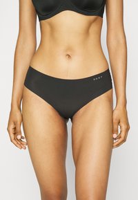 Črne bombažne spodnje hlače z brezšivnim dizajnom, nizkim pasom in DKNY logotipom ob strani. Gladka tekstura, prilegajoča silhueta.