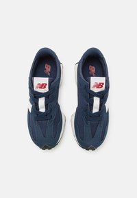 Mornariće plave tenisice s mrežastim gornjim dijelom, bijelim vezicama i logom na jeziku. Potplat je bijel s crnim naglaskom.