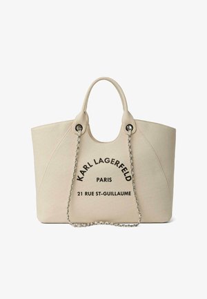 Beige tote tas met afgeronde handvatten, zilveren kettingriem en zwarte tekst aan de voorkant met de tekst "KARL LAGERFELD PARIS 21 RUE ST-GUILLAUME".