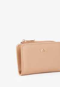 Portafoglio in pelle beige con superficie testurizzata, dotato di logo dorato, chiusura a zip e forma rettangolare compatta.