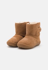 Brune suede ankelstøvler med pelsfôr, rund tå, sydd detaljer og en sidestrikk med logo. Gummiyttersåle for godt grep.