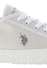 Vita kanvas sneakers med en texturerad yta, med vita snören, silverfärgad logodetalj och en gummisula präglad med "ASSN."