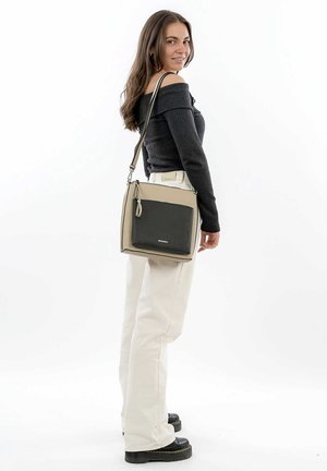 Square crossbody bag featuring a textured dark green front pocket, beige body, adjustable strap, and metal accents.