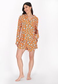 Orange pyjamasset med en knäppning högst upp och huva, tillsammans med matchande shorts, dekorerat med ett mönster av leopardtryck i blått och ljusrosa.