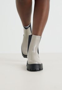 Gray waterproof ankle boots with a sleek design, featuring a sturdy black sole and side panels. Smooth finish with minimal accents.