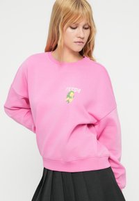 Ροζ φούτερ με γραφιστικό σχέδιο που περιλαμβάνει τη λέξη "FRESH" και μια εικόνα λεμονιού. Κατασκευασμένο από απαλό υλικό με άνετη εφαρμογή.