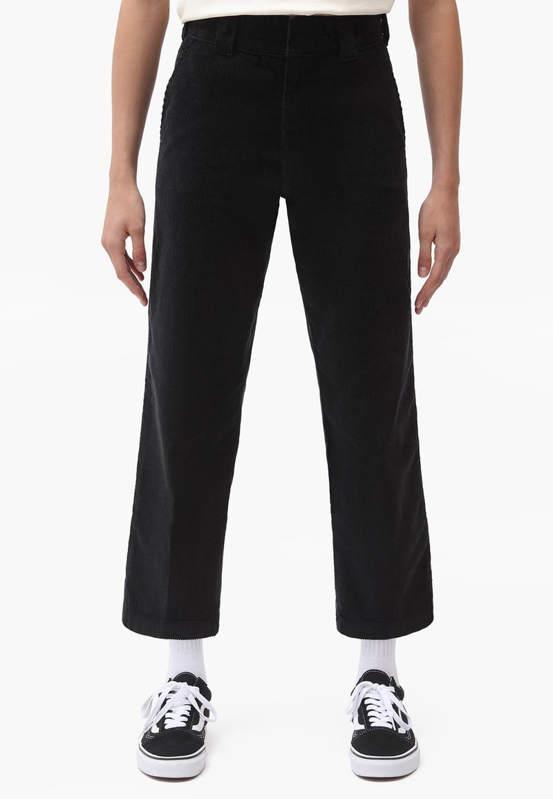 Svart kordfläskbyxor med rak bendesign, med en texturerad yta och femfickorsstil, kombinerat med svarta sneakers och vita strumpor.