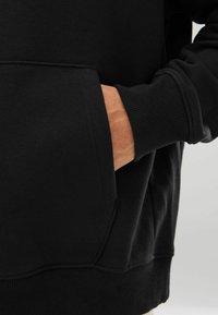 Schwarzer Sweatshirt mit einer Vorderseite Tasche, gerippten Bündchen und Saum. Weicher Stoff und lässiges Design, mit einer lockeren Passform.